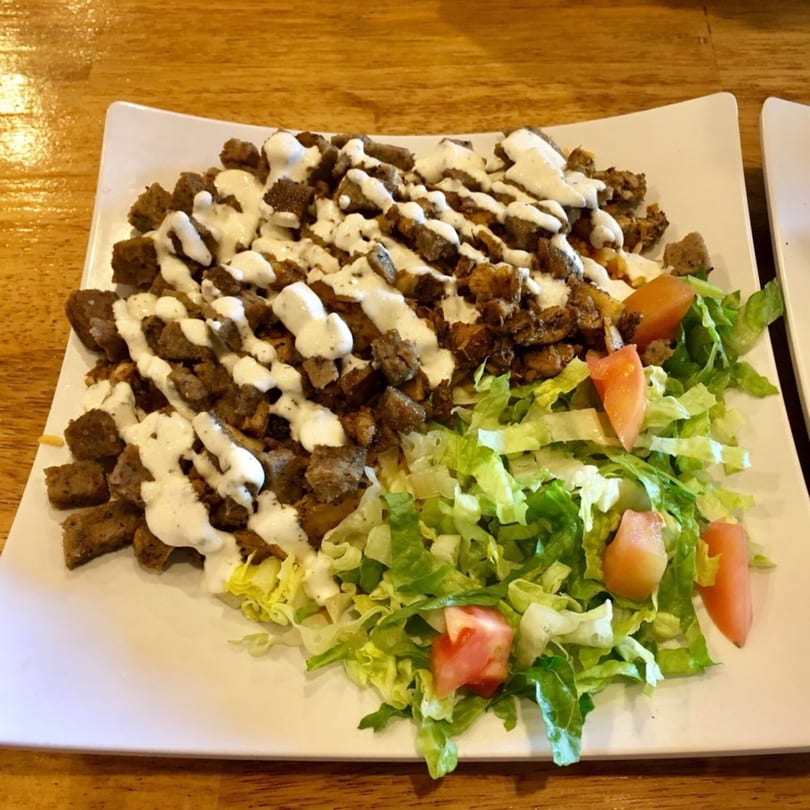 Gyro Grill's gyro meat with white sauce and a side of fresh lettuce and tomato.