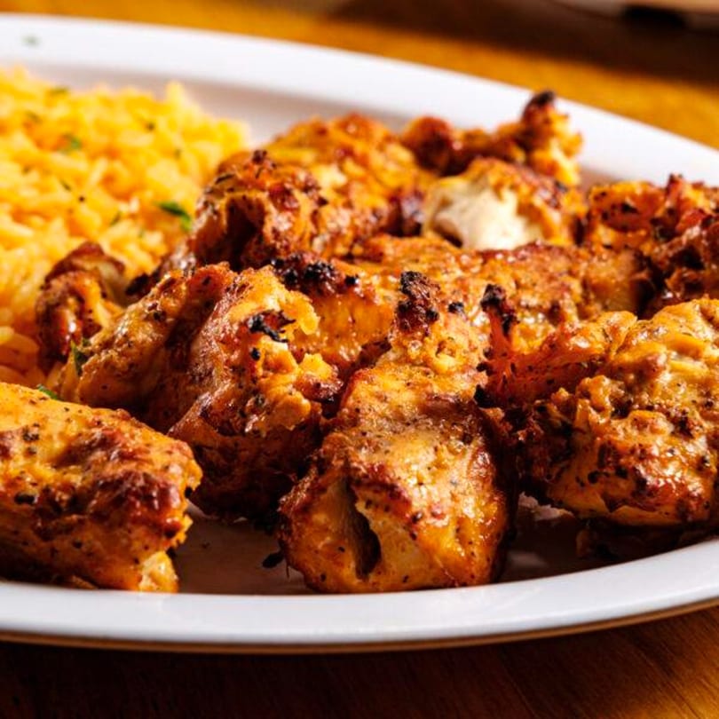 Gyro Grill's chicken shawarma with golden rice, showcasing perfectly grilled, seasoned chicken pieces on a white plate.